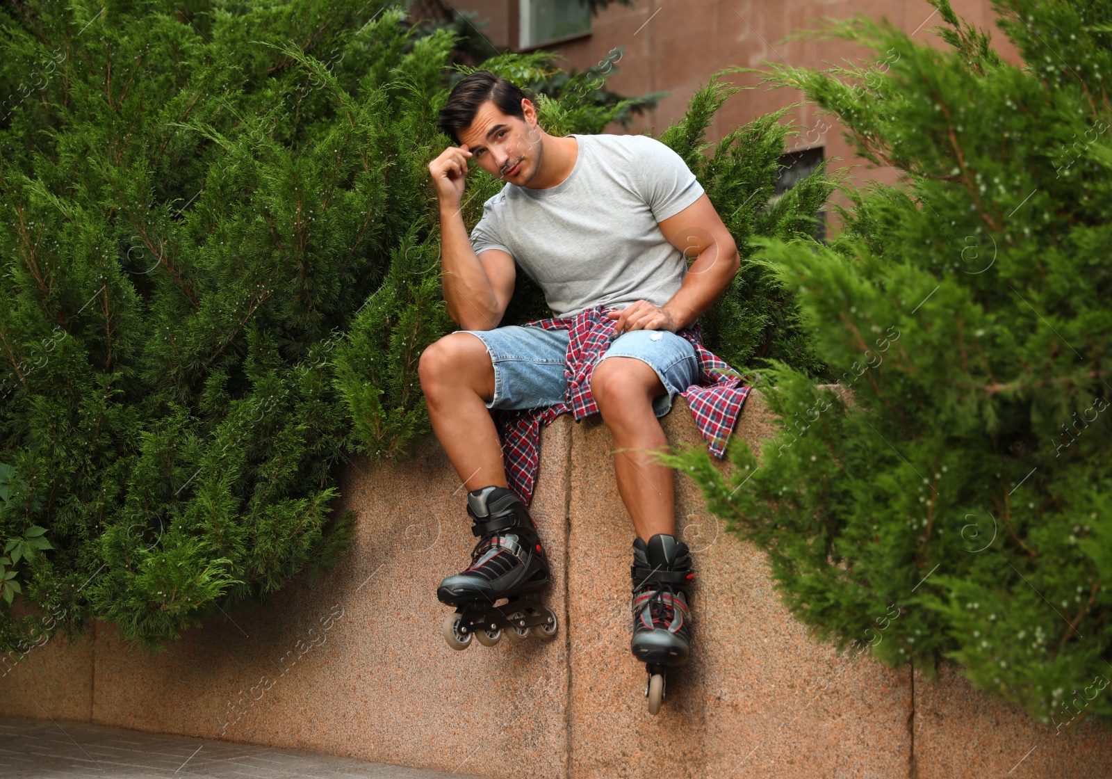 Photo of Handsome young man with roller skates outdoors