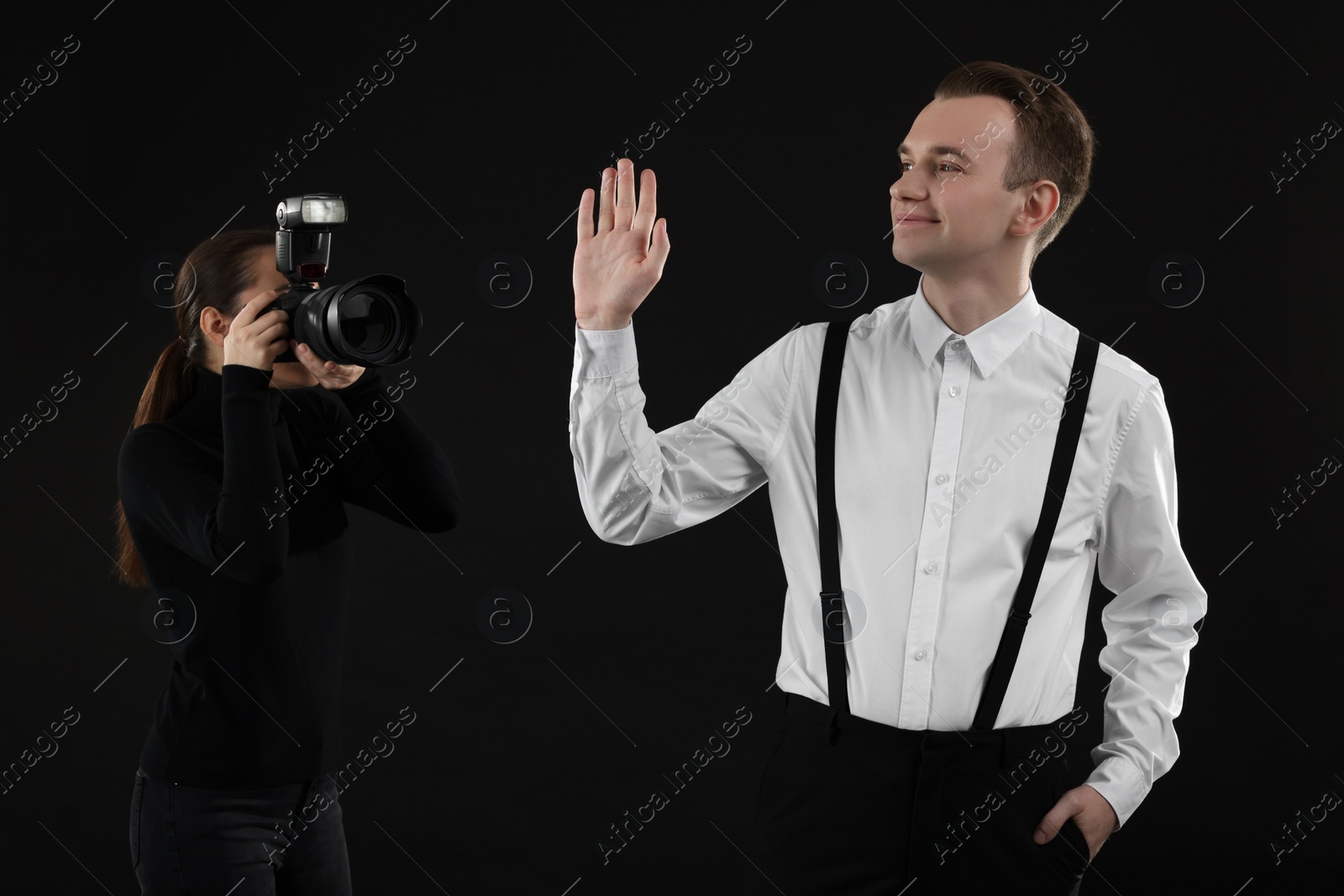 Photo of Professional photographer taking picture of man on black background