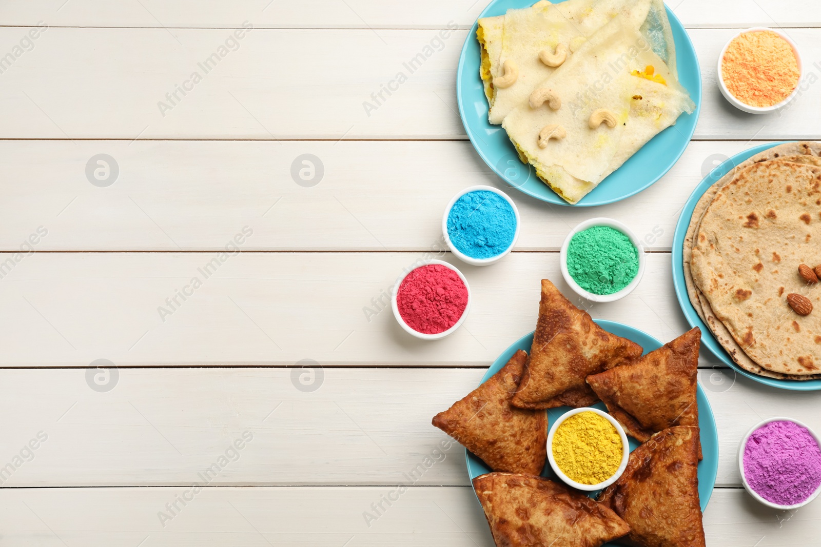 Photo of Traditional Indian food and color powders on white wooden table, flat lay with space for text. Holi festival celebration