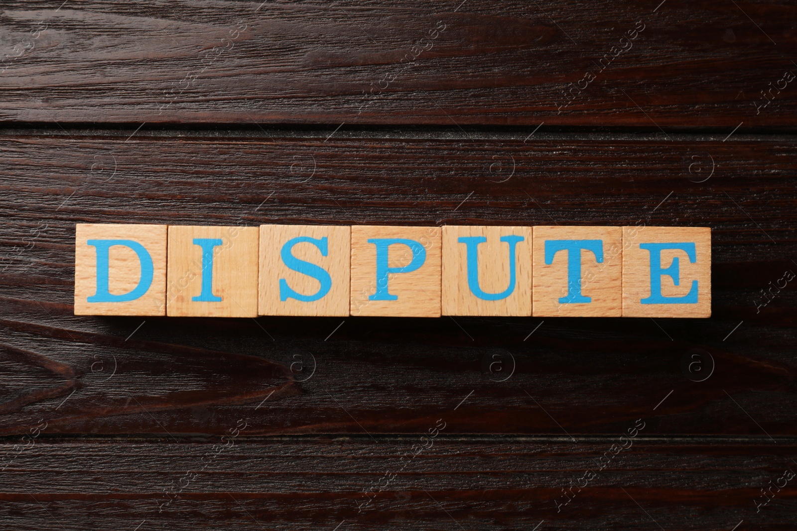 Photo of Cubes with word Dispute on dark wooden table, top view