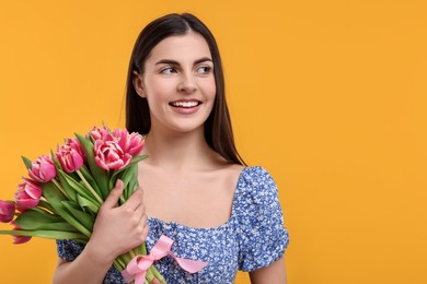 Happy young woman with beautiful bouquet on orange background. Space for text