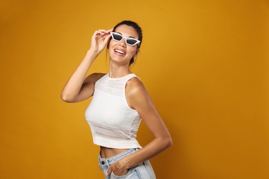 Photo of Beautiful woman in sunglasses on yellow background, space for text