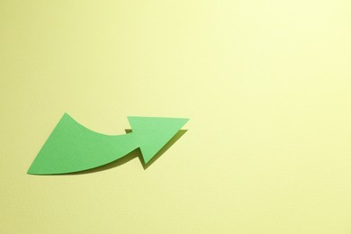 Curved green paper arrow on yellow background, above view. Space for text
