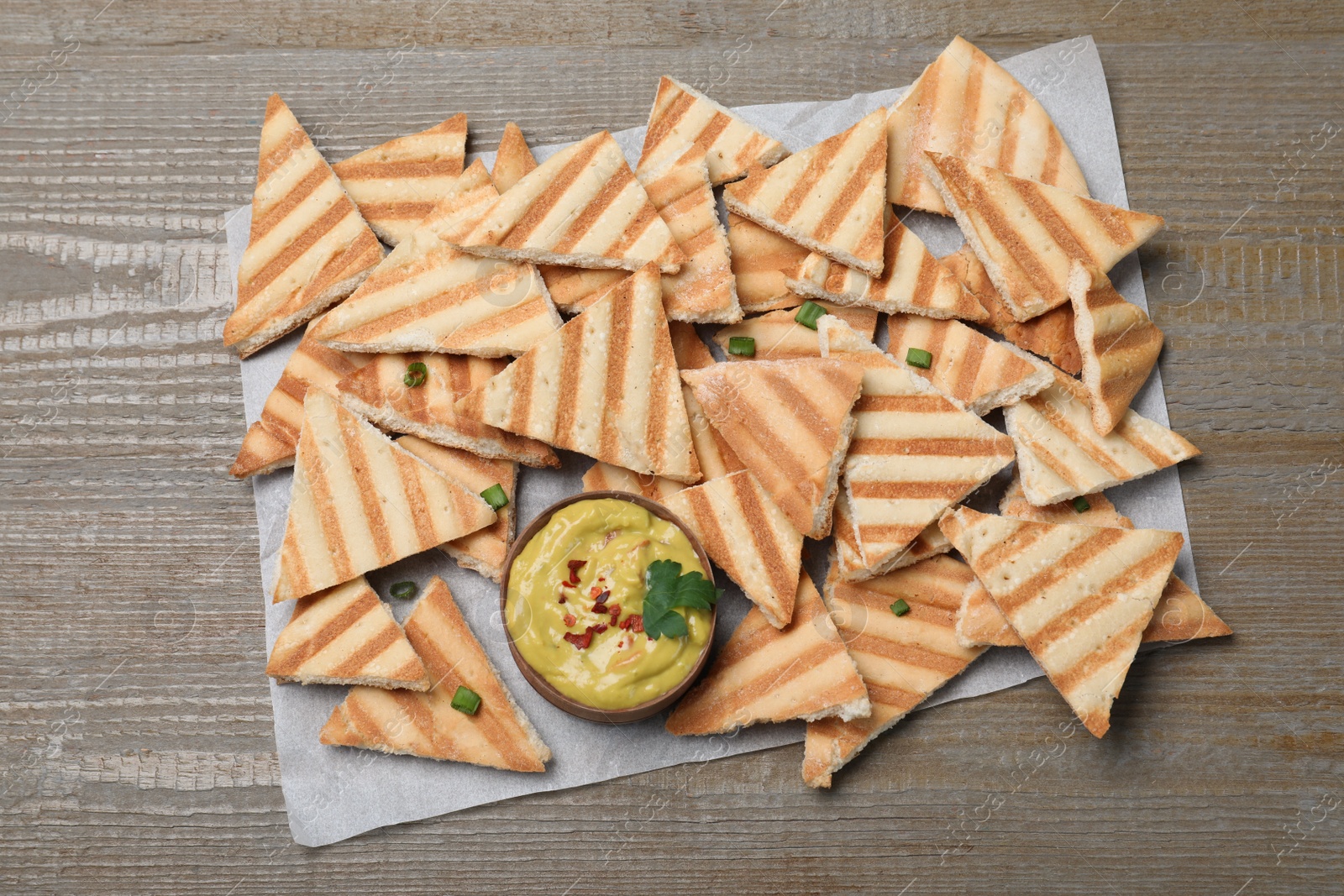 Photo of Delicious pita chips and hummus on wooden table, top view