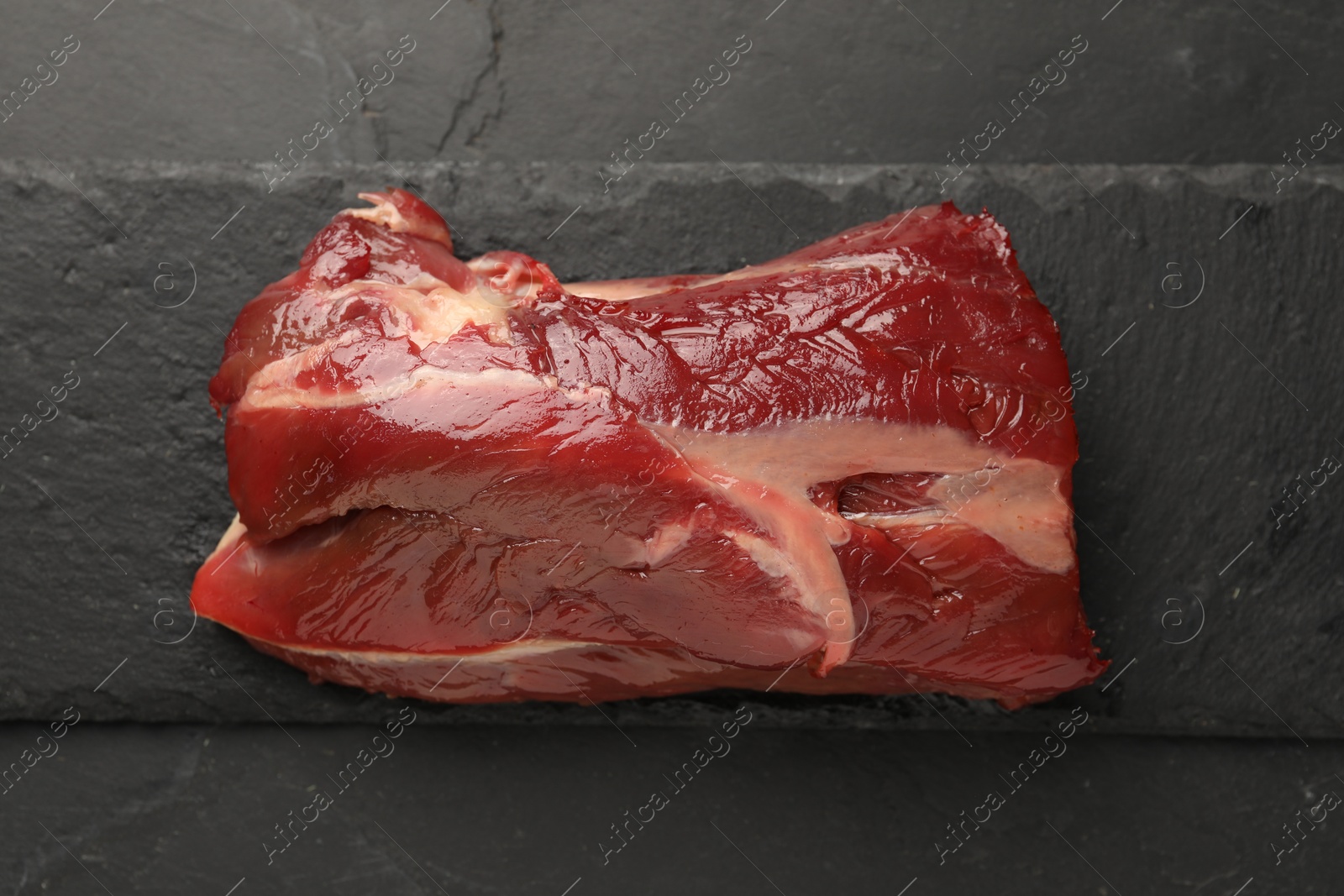 Photo of Piece of raw beef meat on black table, top view