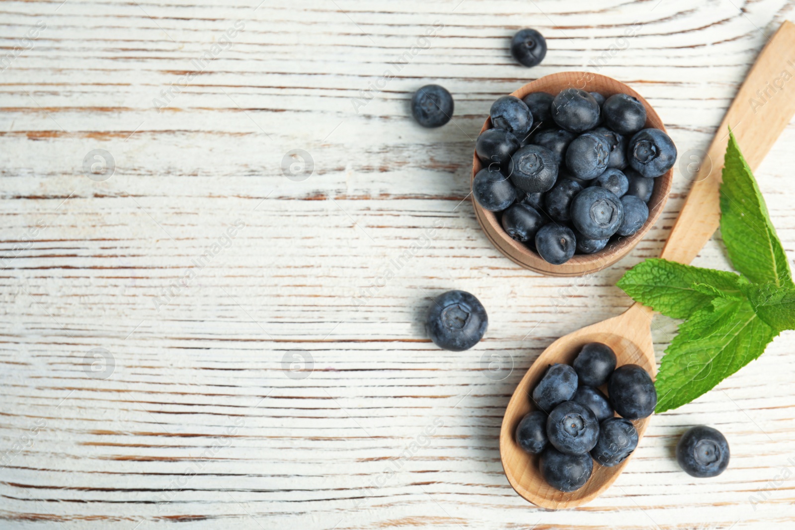 Photo of Flat lay composition of tasty blueberries and space for text on white wooden table