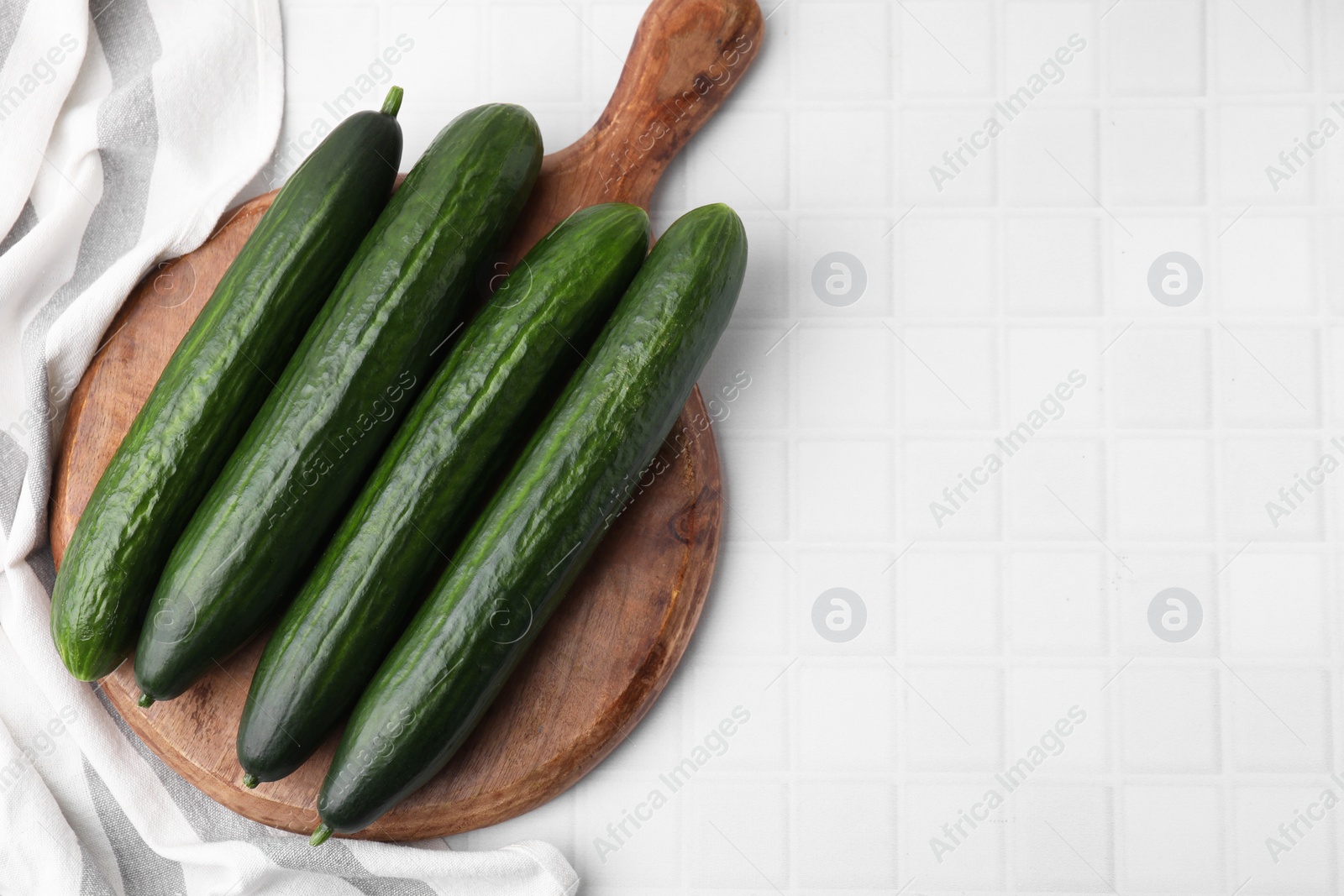 Photo of Fresh cucumbers on white tiled table, top view. Space for text