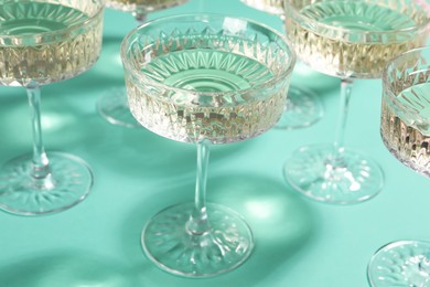 Photo of Glasses of expensive white wine on turquoise background