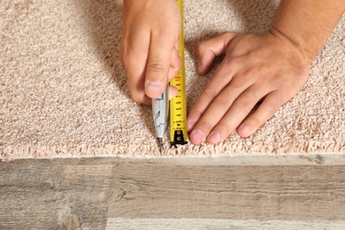 Man cutting new carpet flooring indoors, closeup