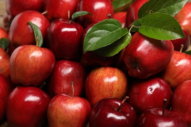 Photo of Fresh ripe red apples with leaves as background, closeup