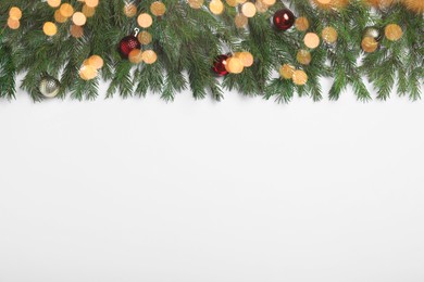 Flat lay composition with fir tree branches and Christmas decor on white background, space for text. Bokeh effect