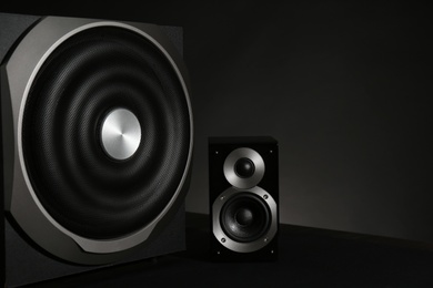 Photo of Modern powerful audio speaker and subwoofer on black background. Space for text