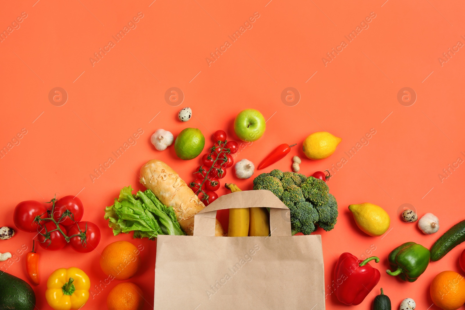 Photo of Paper bag with different groceries on coral background, flat lay