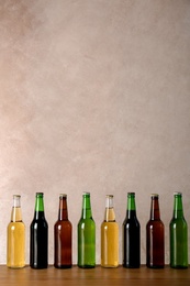 Photo of Bottles with different beer on table against color background