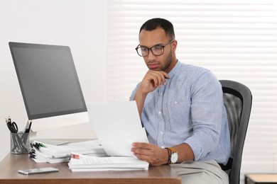 Businessman working with documents at wooden table in office