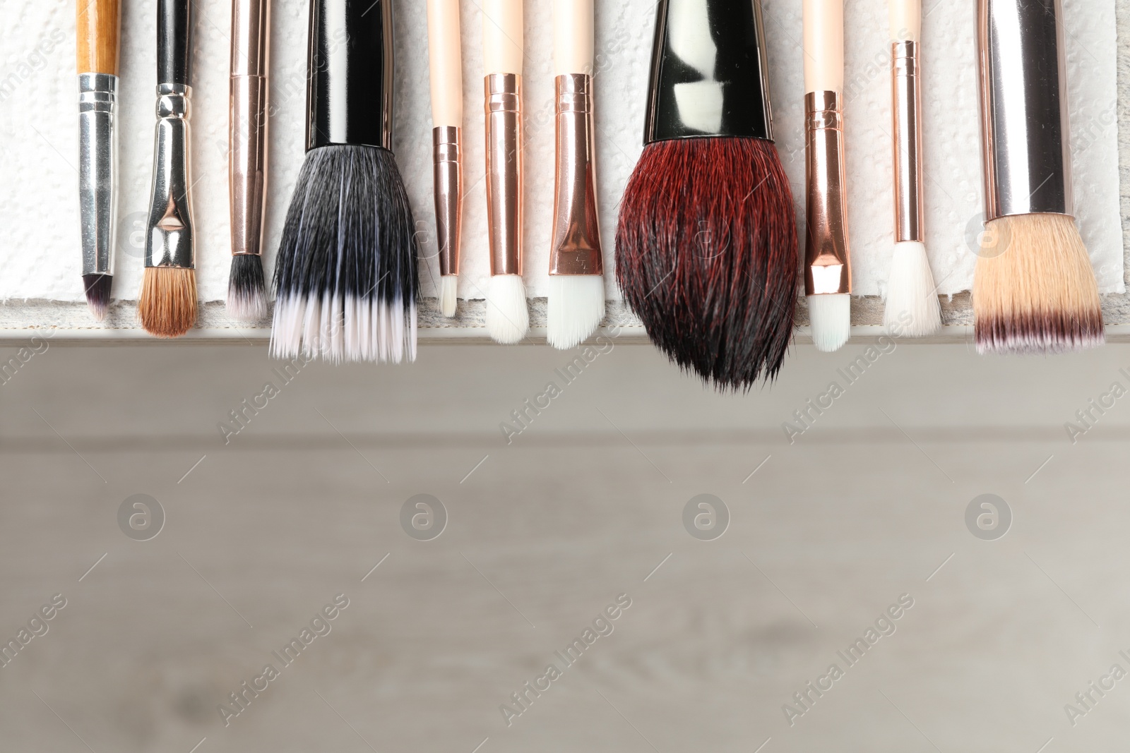 Photo of Set of different makeup brushes drying after cleaning on table, flat lay. Space for text