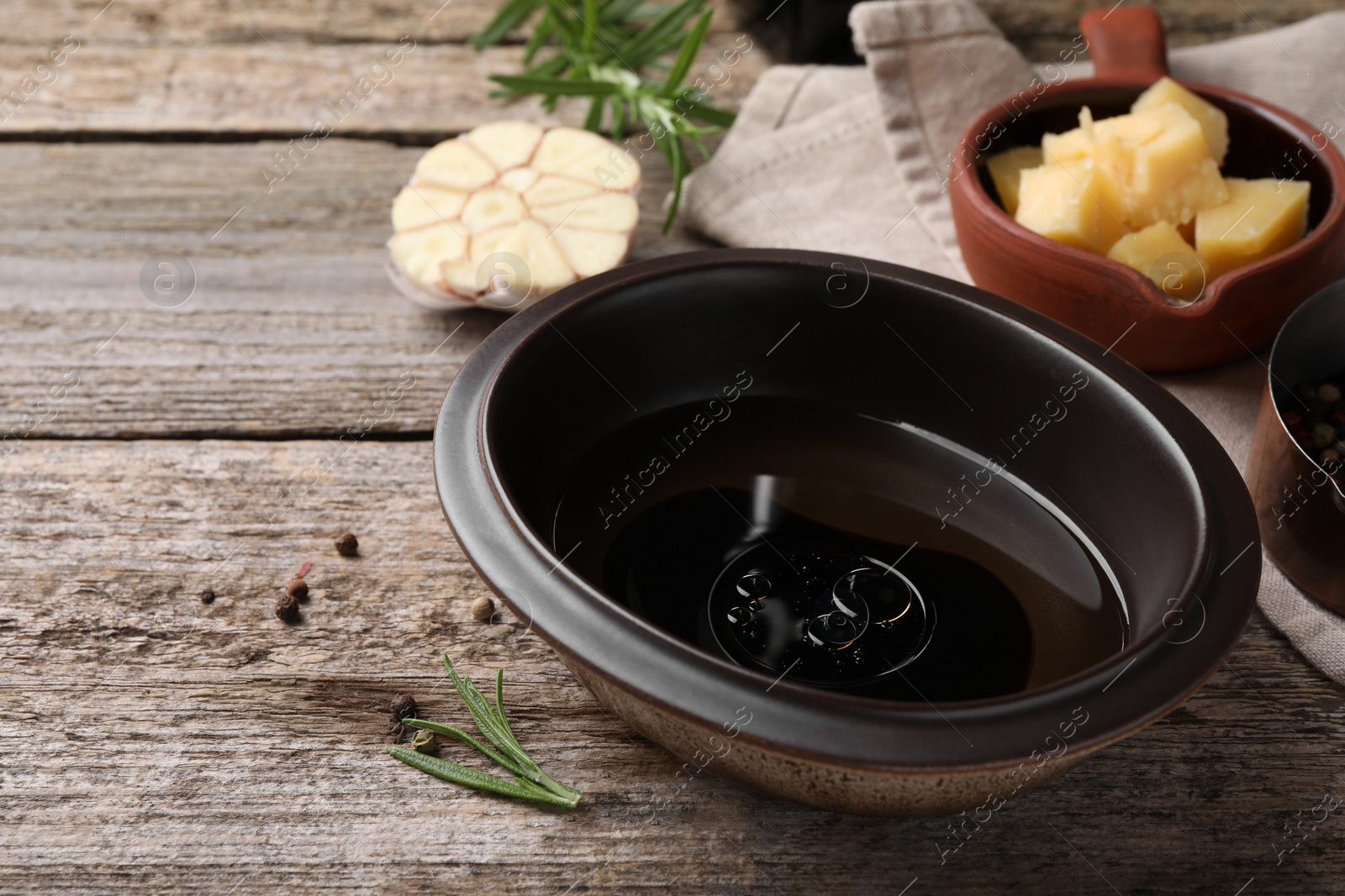 Photo of Bowl of balsamic vinegar with oil on wooden table, closeup. Space for text