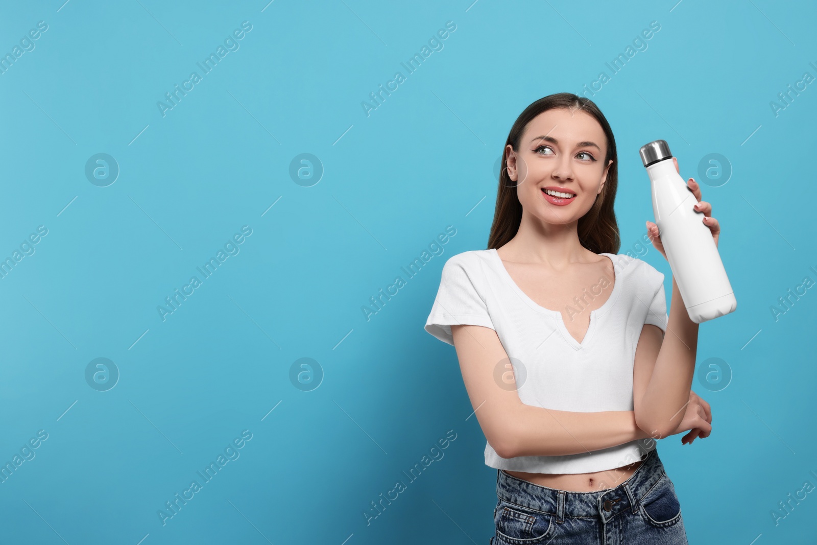 Photo of Beautiful young woman with thermos bottle on light blue background, space for text