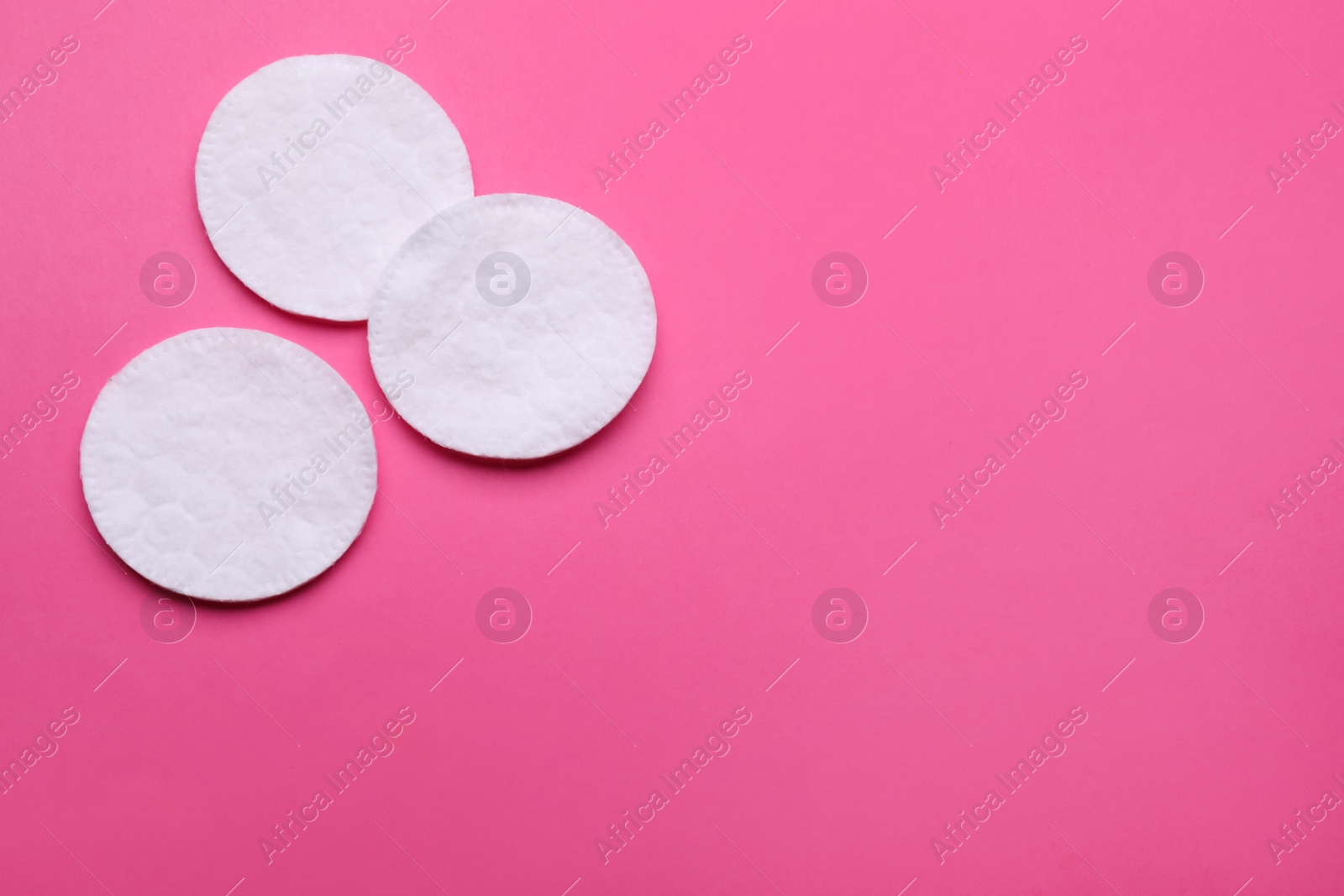 Photo of Clean cotton pads on pink background, flat lay. Space for text
