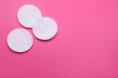 Clean cotton pads on pink background, flat lay. Space for text