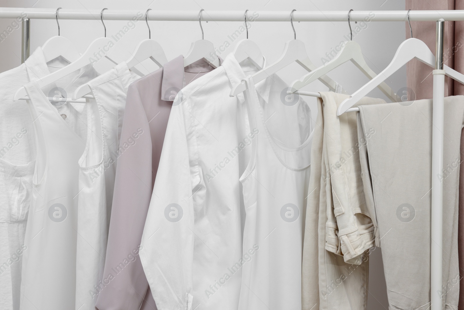 Photo of Rack with different stylish women`s clothes near white wall