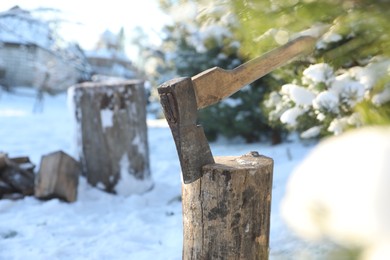 Metal axe in wooden log outdoors on sunny winter day. Space for text