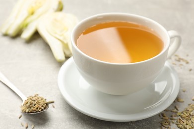 Photo of Aromatic fennel tea, seeds and fresh vegetable on grey table, closeup