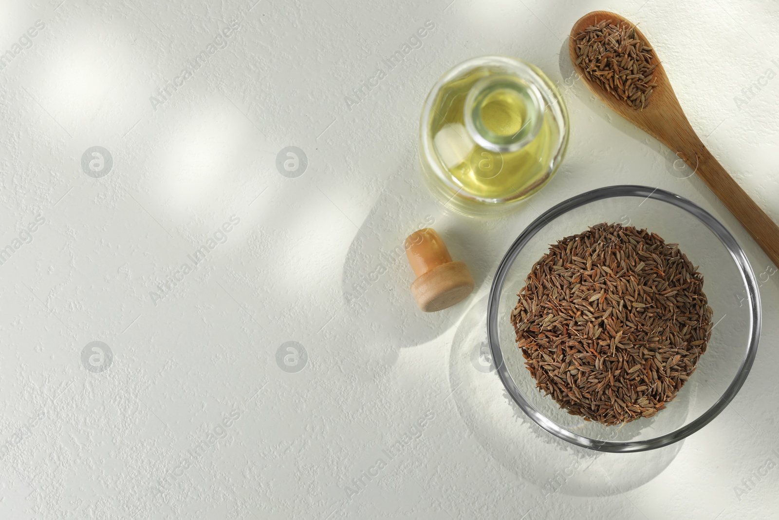 Photo of Caraway (Persian cumin) seeds and essential oil on white table, flat lay. Space for text