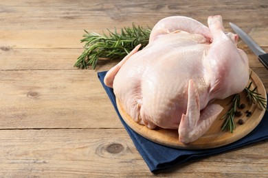 Photo of Fresh raw chicken with spices and knife on wooden table, space for text