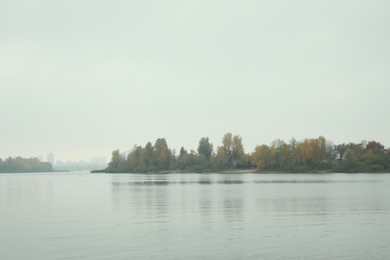 Tranquil lake and shore with trees under sky