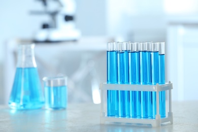 Photo of Test tubes with light blue liquid on table in laboratory. Space for text