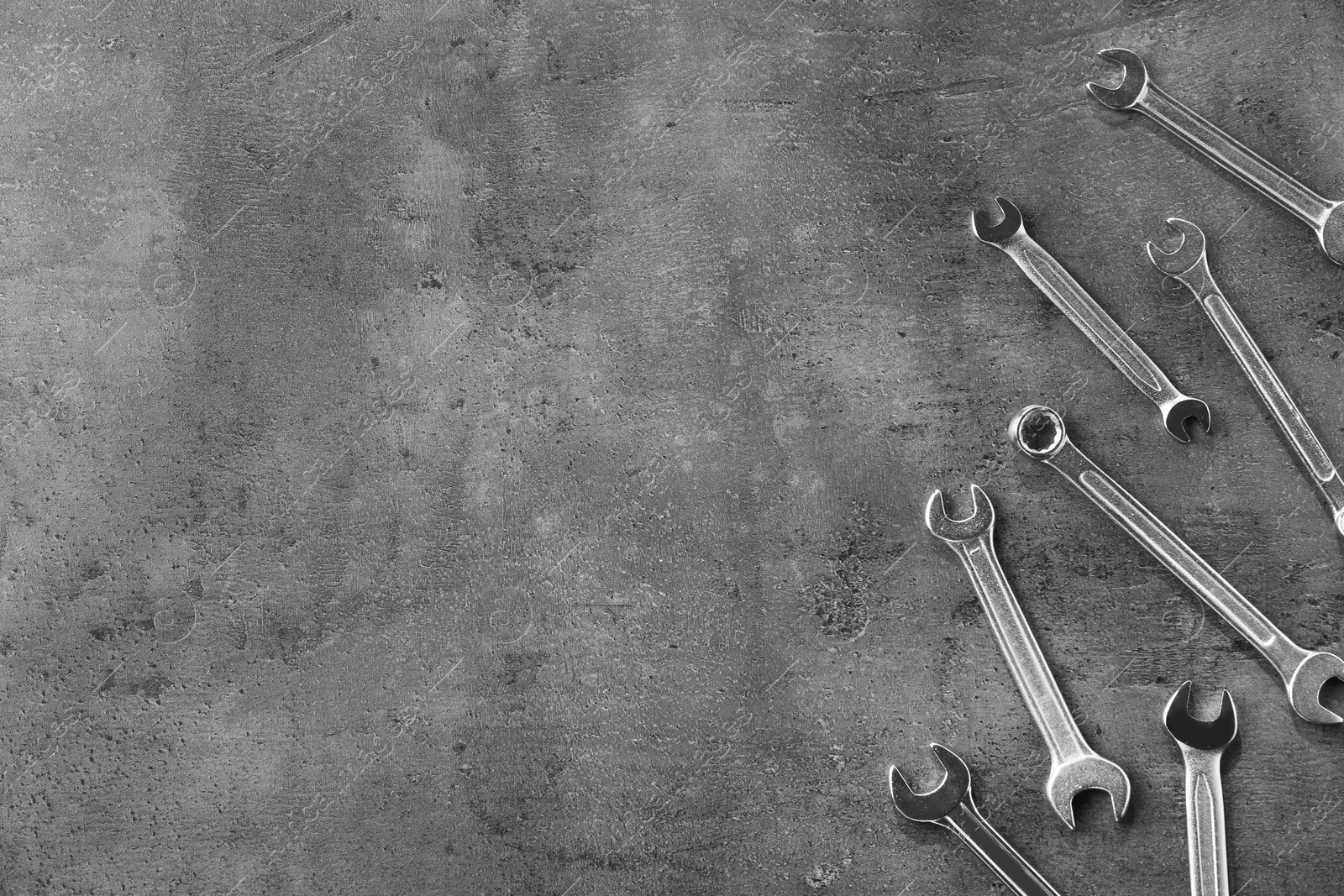 Photo of New wrenches on grey background, top view with space for text. Plumber tools