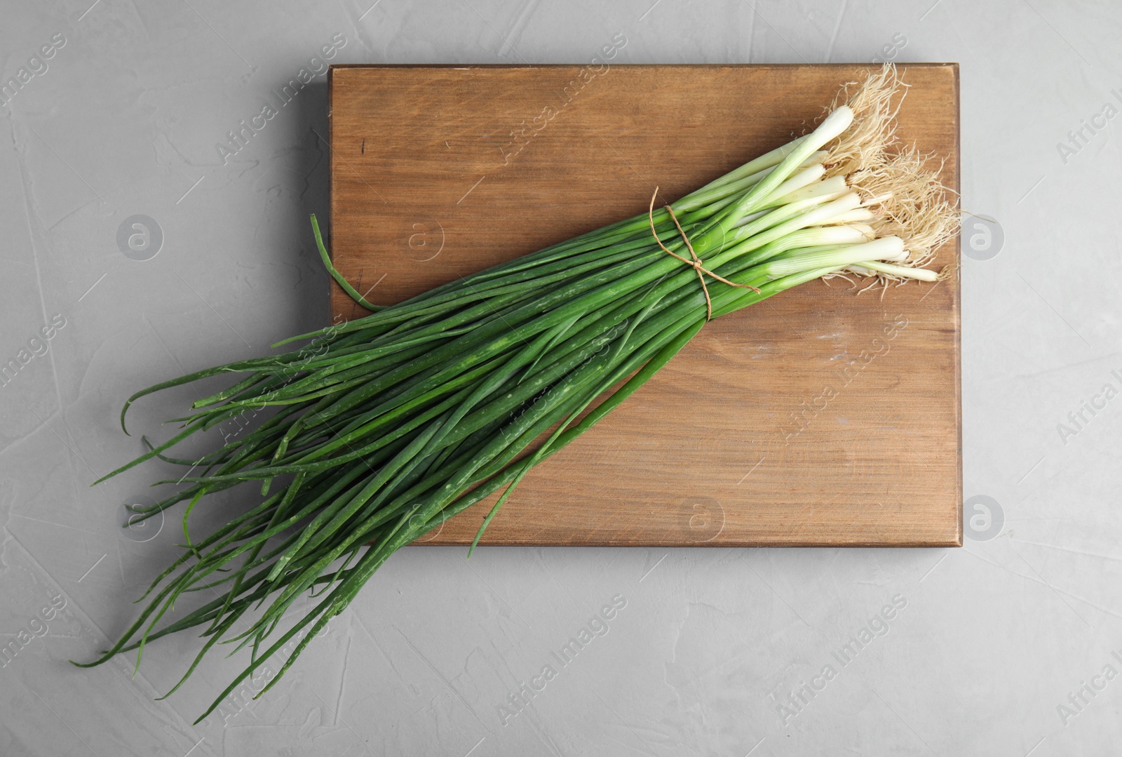 Photo of Fresh green onion on wooden board, top view