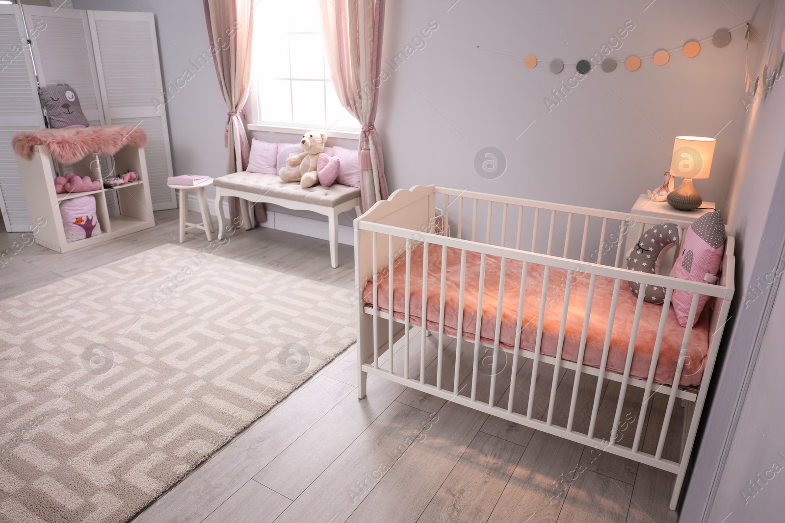 Photo of Baby room interior with comfortable crib and indoor bench