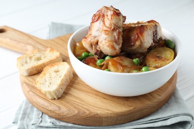 Photo of Tasty cooked rabbit with vegetables in bowl and bread on table, closeup