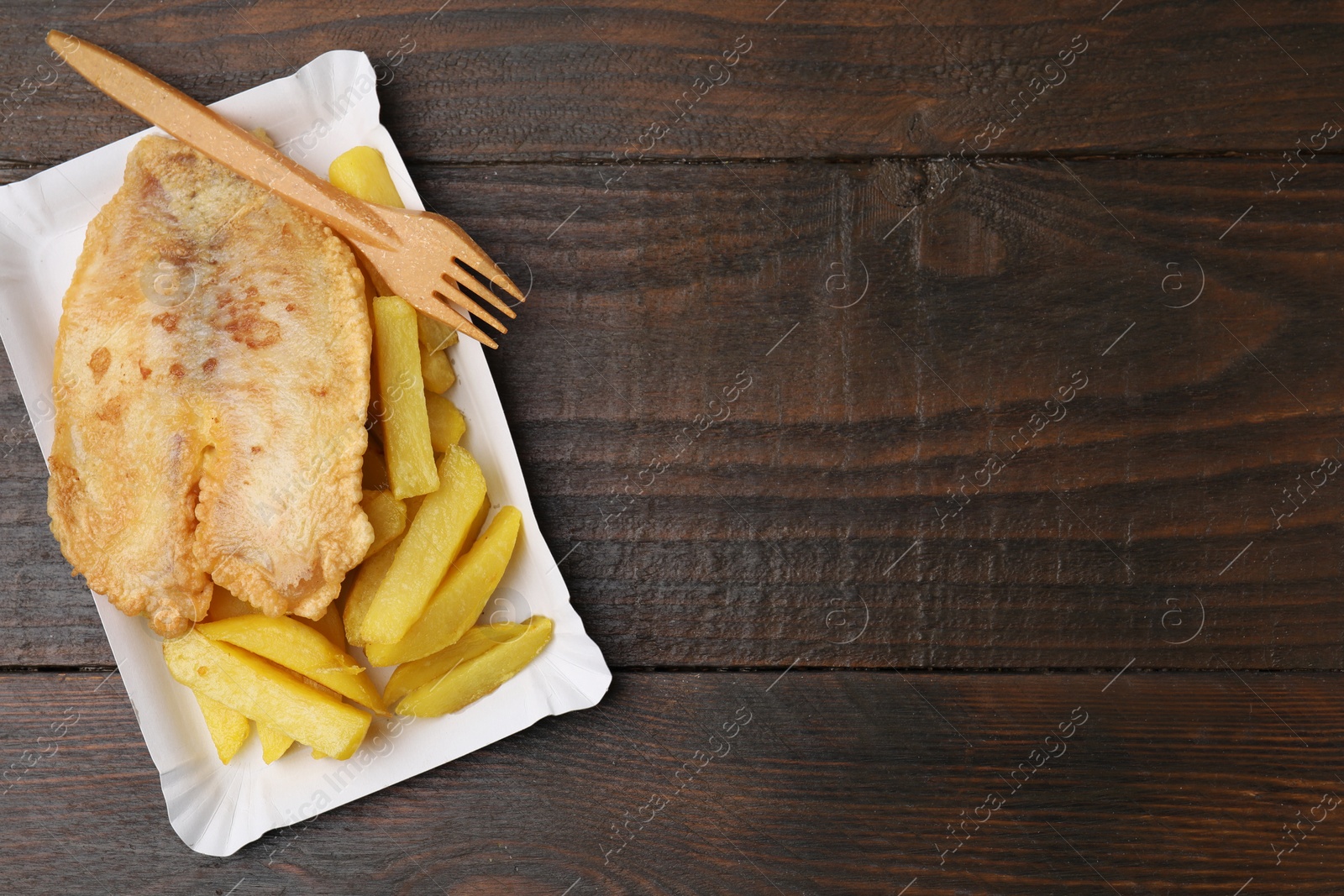 Photo of Delicious fish and chips served on wooden table, top view. Space for text