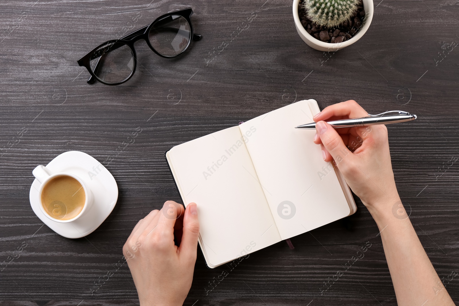 Photo of Woman with notebook and pen at grey wooden table, top view. Space for text