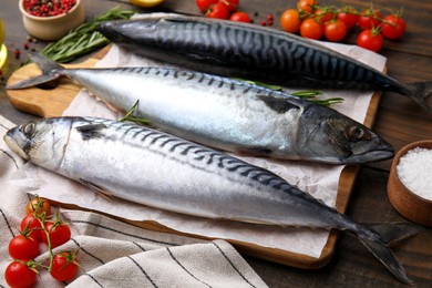 Raw mackerel, tomatoes and salt on wooden table