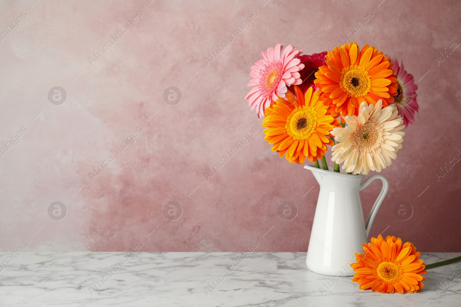 Photo of Bouquet of beautiful bright gerbera flowers in vase on marble table against color background
