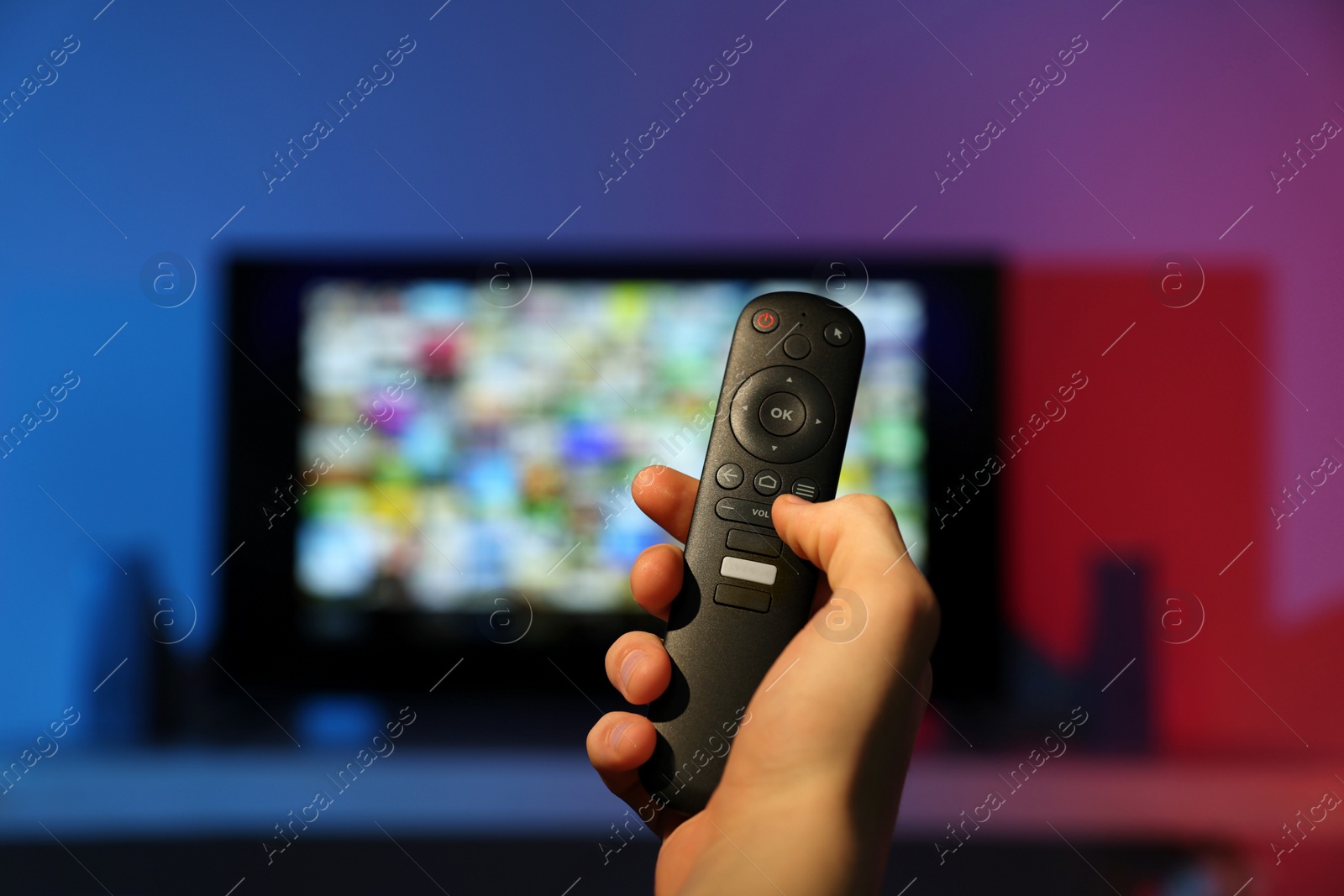 Photo of Woman switching channels on TV set with remote control at home, closeup