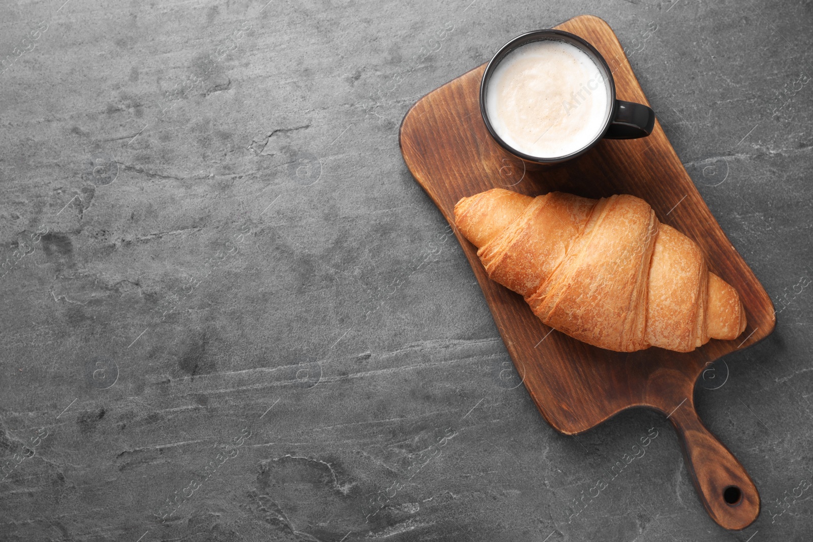 Photo of Tasty fresh croissant and coffee on grey table, top view. Space for text
