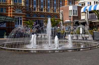 Beautiful fountain near buildings on city street