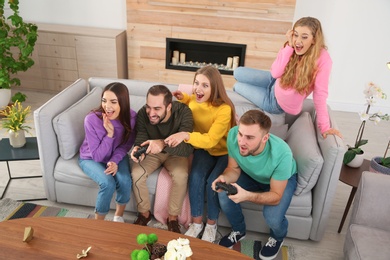 Photo of Group of friends engaged in video game indoors. Celebrating victory