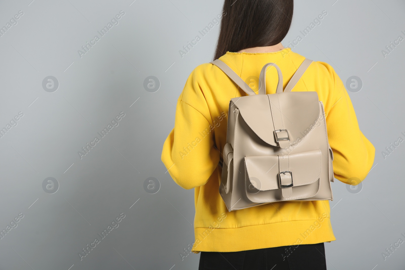 Photo of Young woman with stylish leather backpack on grey background, back view. Space for text