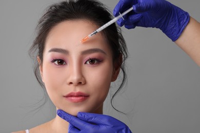 Photo of Woman getting facial injection on grey background