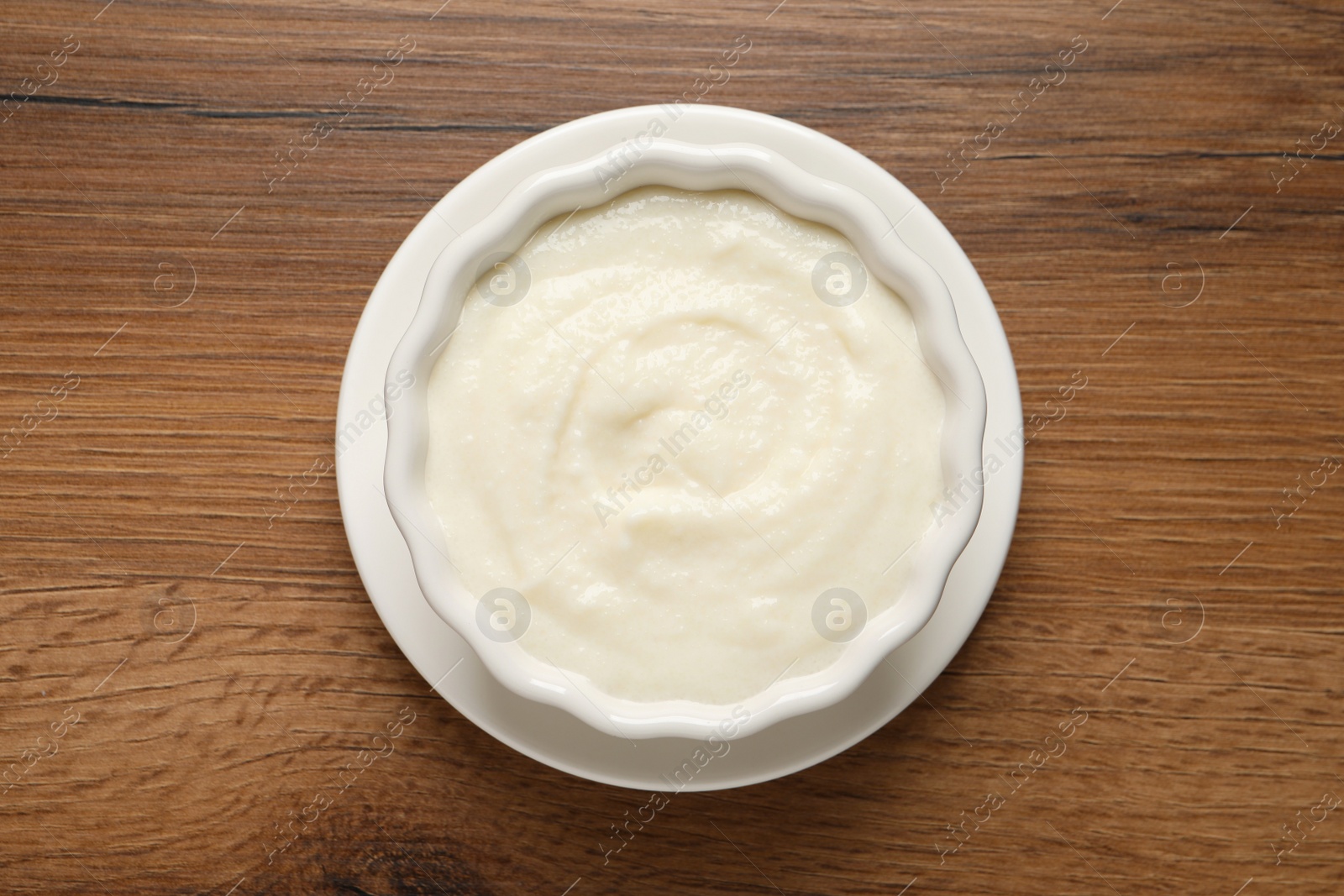 Photo of Bowl with delicious semolina pudding on wooden table, top view