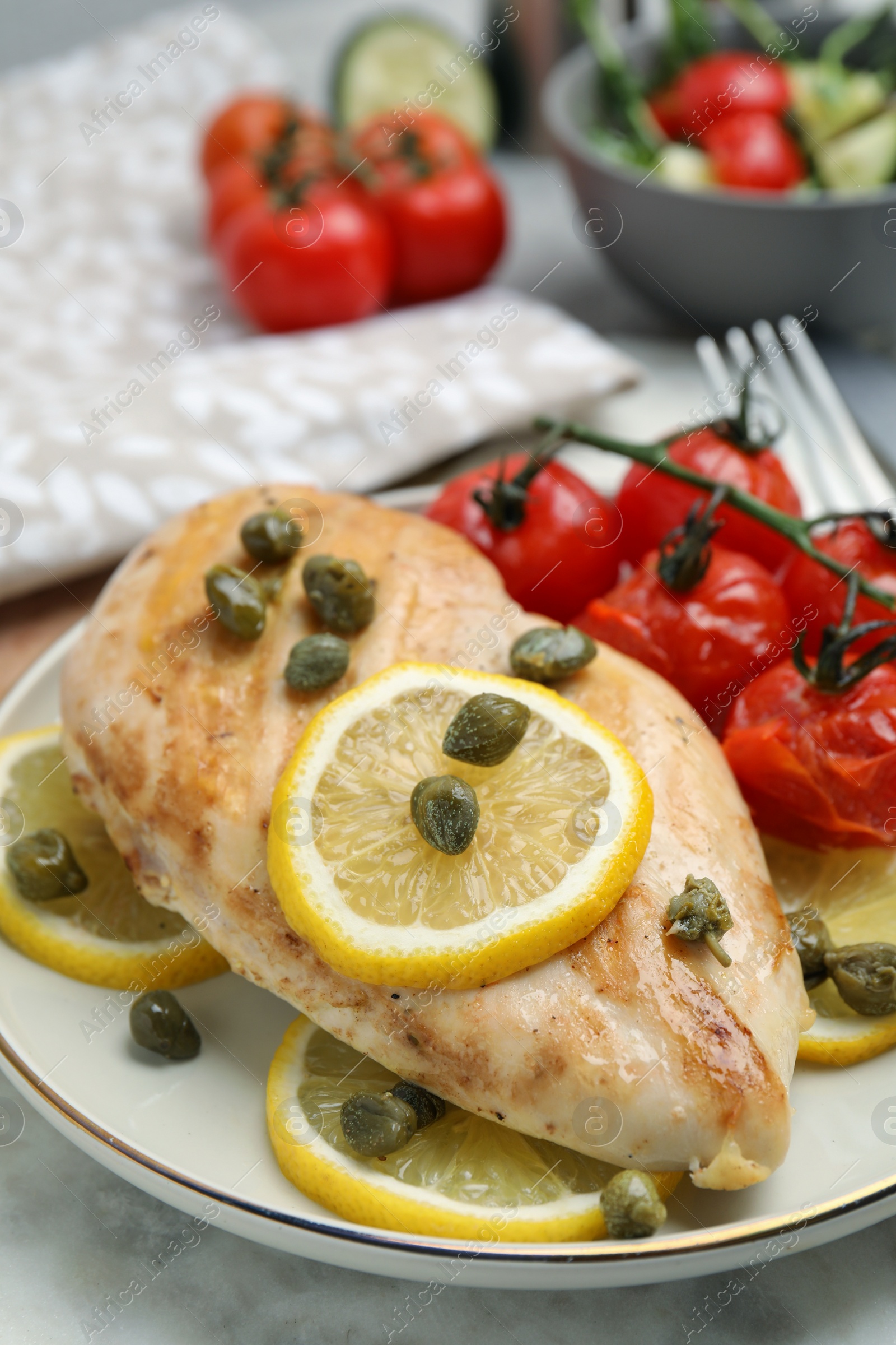 Photo of Delicious cooked chicken fillet with capers, tomatoes and lemon on table, closeup