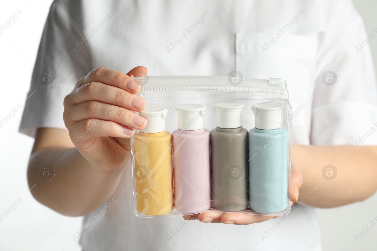 Photo of Woman with cosmetic travel kit on white background, closeup