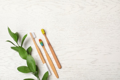 Flat lay composition with bamboo toothbrushes and space for text on white wooden background