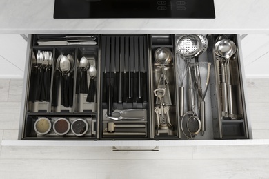 Open drawer with stainless steel utensil set. Order in kitchen